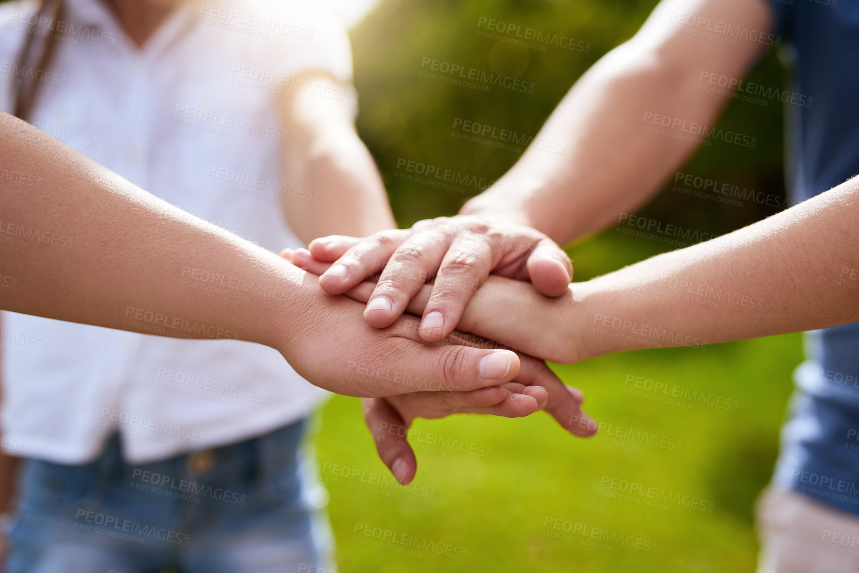 Buy stock photo Closeup of a group of people forming a huddle with their hands while standing outside in a park during the day
