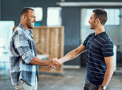 Buy stock photo Shot of two young designers shaking hands in an office