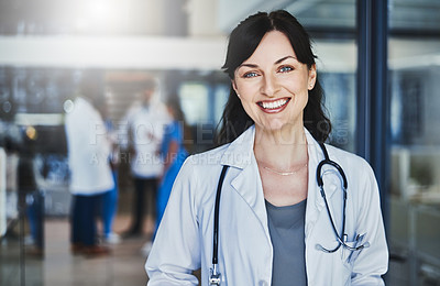 Buy stock photo Portrait of a confident doctor working in a hospital with her colleagues in the background