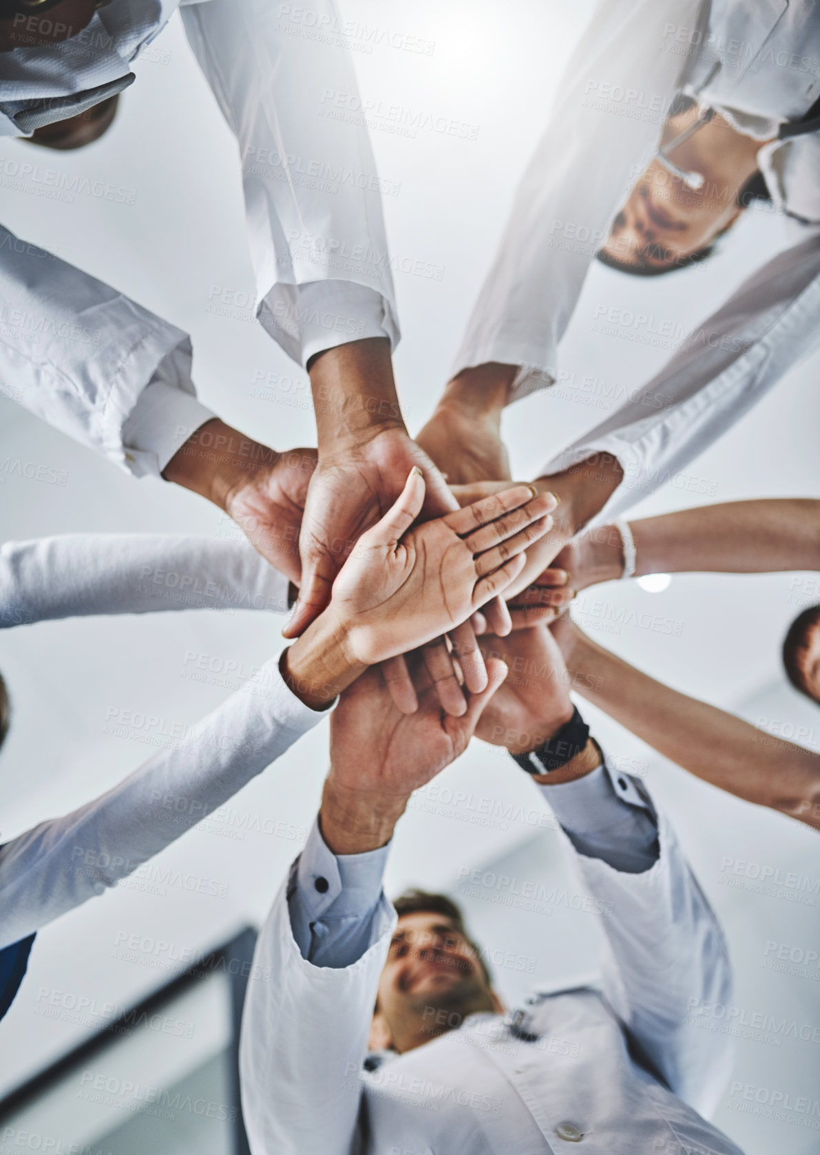 Buy stock photo Low angle shot of a diverse team of doctors joining their hands together in a hospital