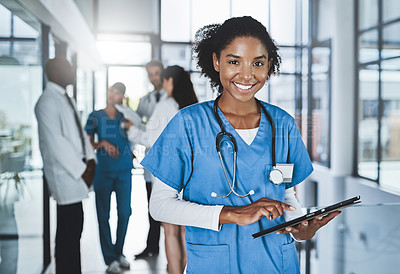 Buy stock photo Portrait of a young doctor using a digital tablet in a hospital with her colleagues in the background