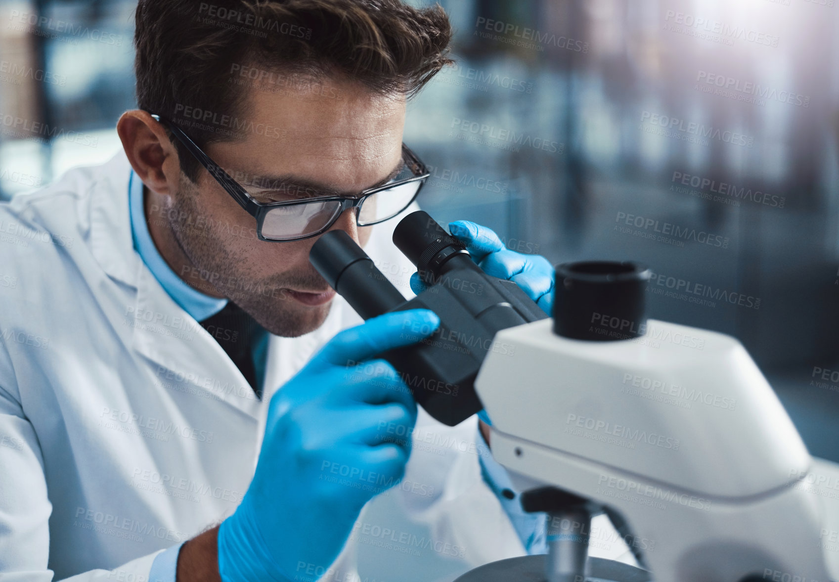 Buy stock photo Cropped shot of a young male scientist working in a lab with a microscope