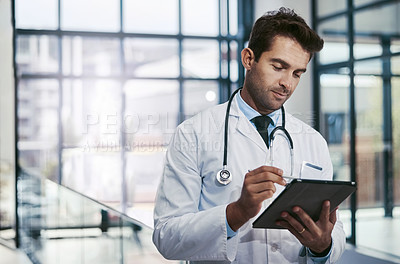 Buy stock photo Cropped shot of a young handsome male medical practitioner working in a hospital