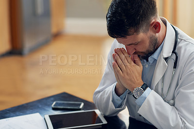Buy stock photo High angle shot of a handsome male doctor praying while sitting in his office