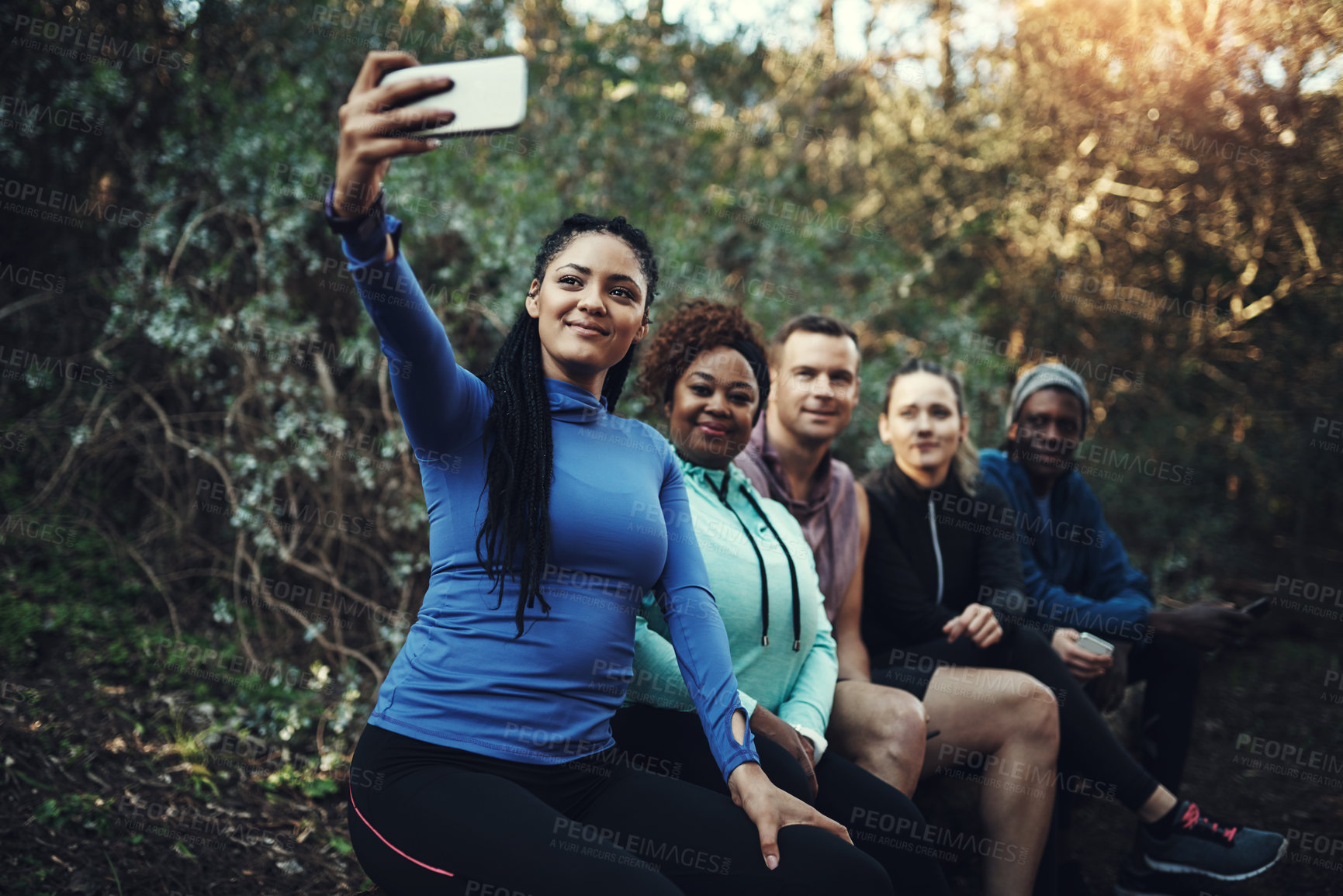 Buy stock photo Cropped shot of a sporty young group of friends taking a selfie while taking a break during a workout in the forest