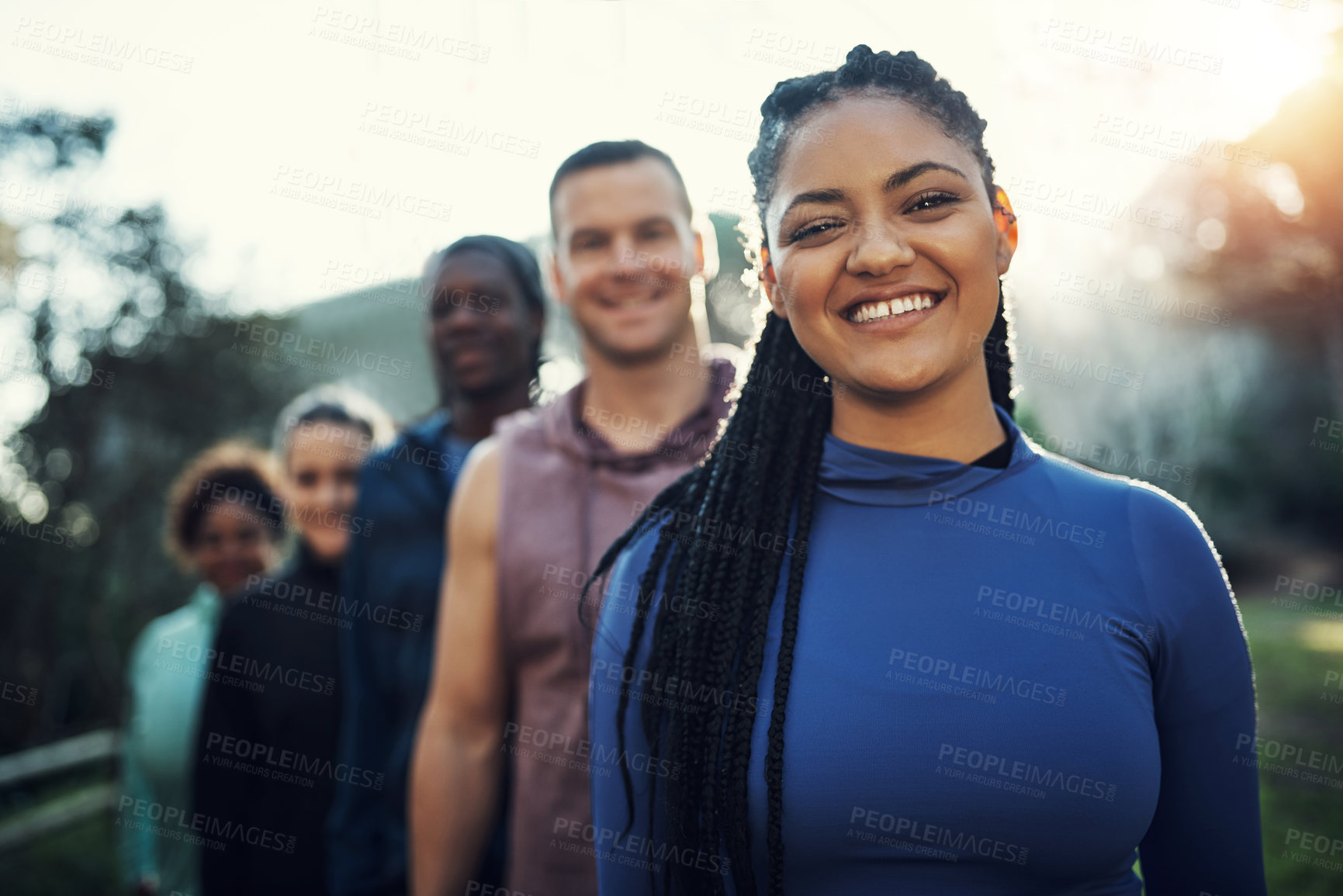 Buy stock photo Portrait of a group of sporty young friends standing in a row while working out in the forest