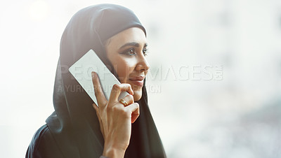 Buy stock photo Cropped shot of an attractive young businesswoman dressed in Islamic traditional clothing making a phonecall while standing on her office balcony