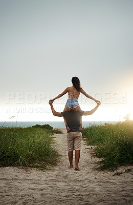 Buy stock photo Rearview shot of a happy young couple having fun at the beach