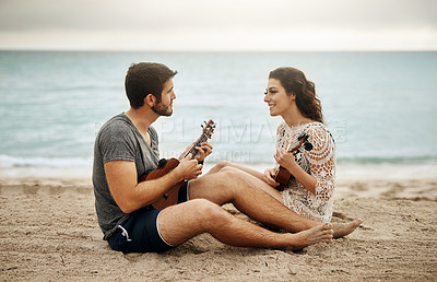 Buy stock photo Shot of a young couple playing the ukulele on the beach