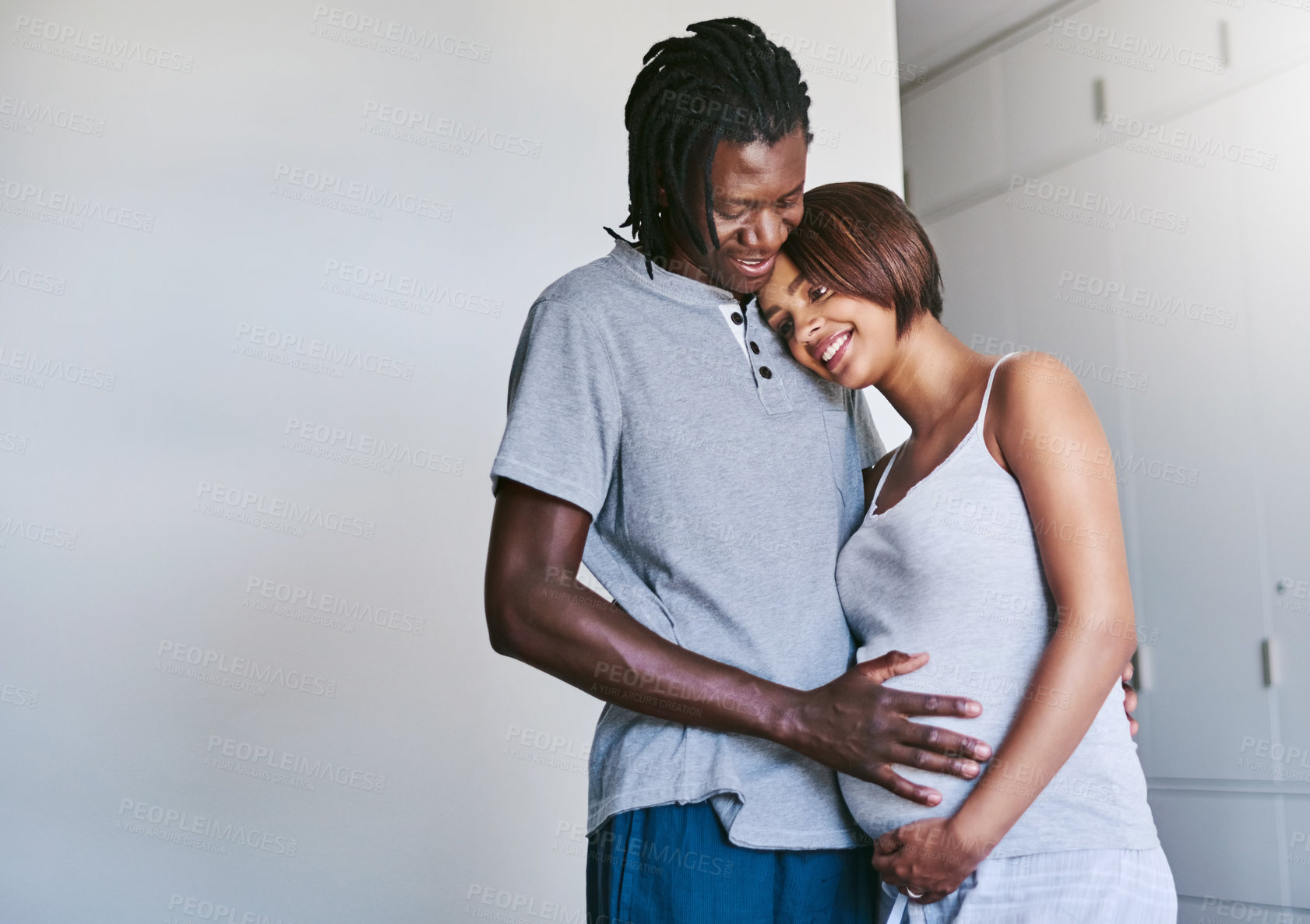 Buy stock photo Shot of a young man touching his pregnant wife's belly