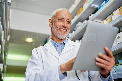 Buy stock photo Shot of a mature pharmacist using a digital tablet in a pharmacy