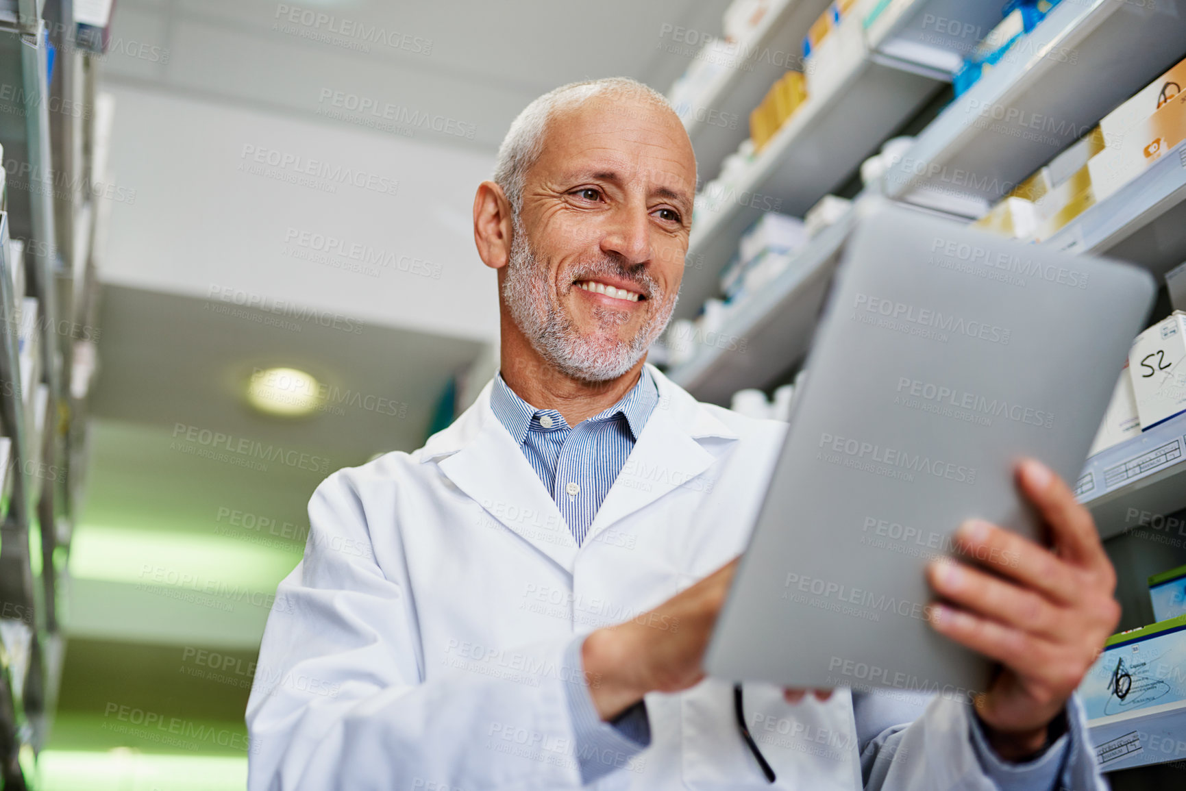 Buy stock photo Shot of a mature pharmacist using a digital tablet in a pharmacy