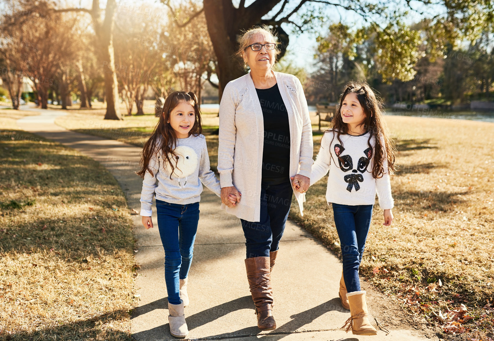 Buy stock photo Shot of a grandmother walking with her adorable granddaughters outdoors