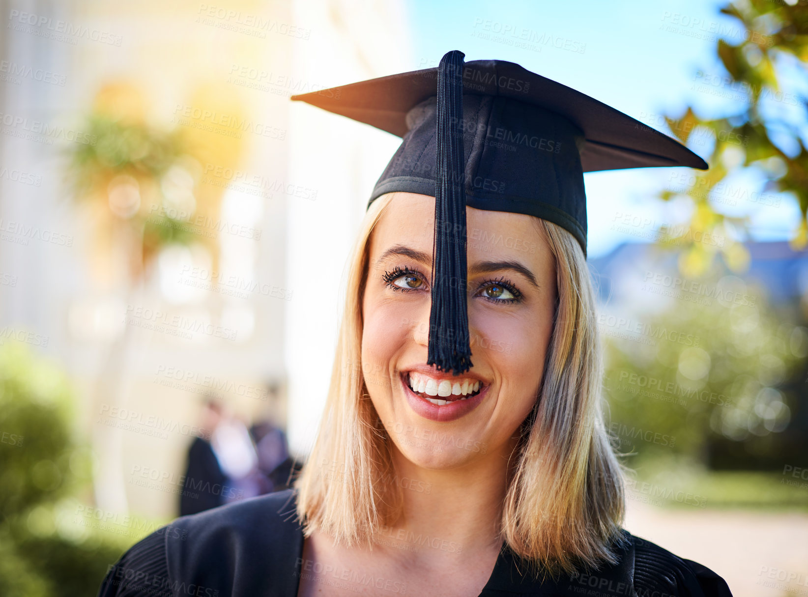 Buy stock photo Cropped shot of a happy young woman standing outside on graduation day
