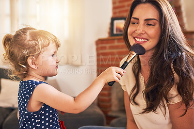 Buy stock photo Shot of an adorable little girl applying makeup to her mother’s face at home