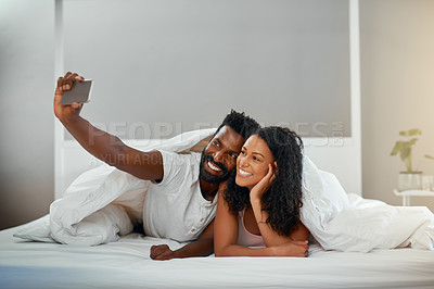 Buy stock photo Cropped shot of a young attractive couple taking a selfie in bed at home