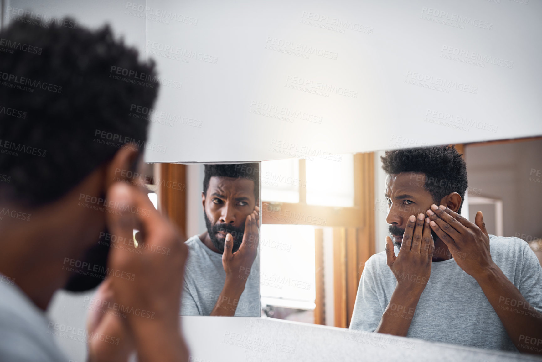 Buy stock photo Cropped shot of a handsome young man examining his face in a mirror in the bathroom at home