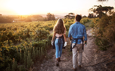 Buy stock photo Rearview shot of a young man and woman walking through a farm