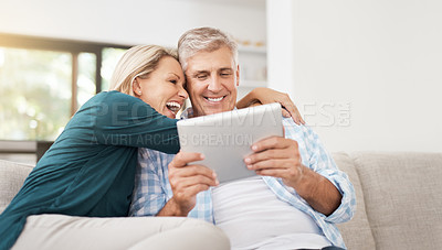 Buy stock photo Cropped shot of an affectionate mature couple using a tablet while sitting on their sofa at home
