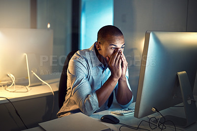Buy stock photo Shot of a young businessman looking stressed out while working late in an office