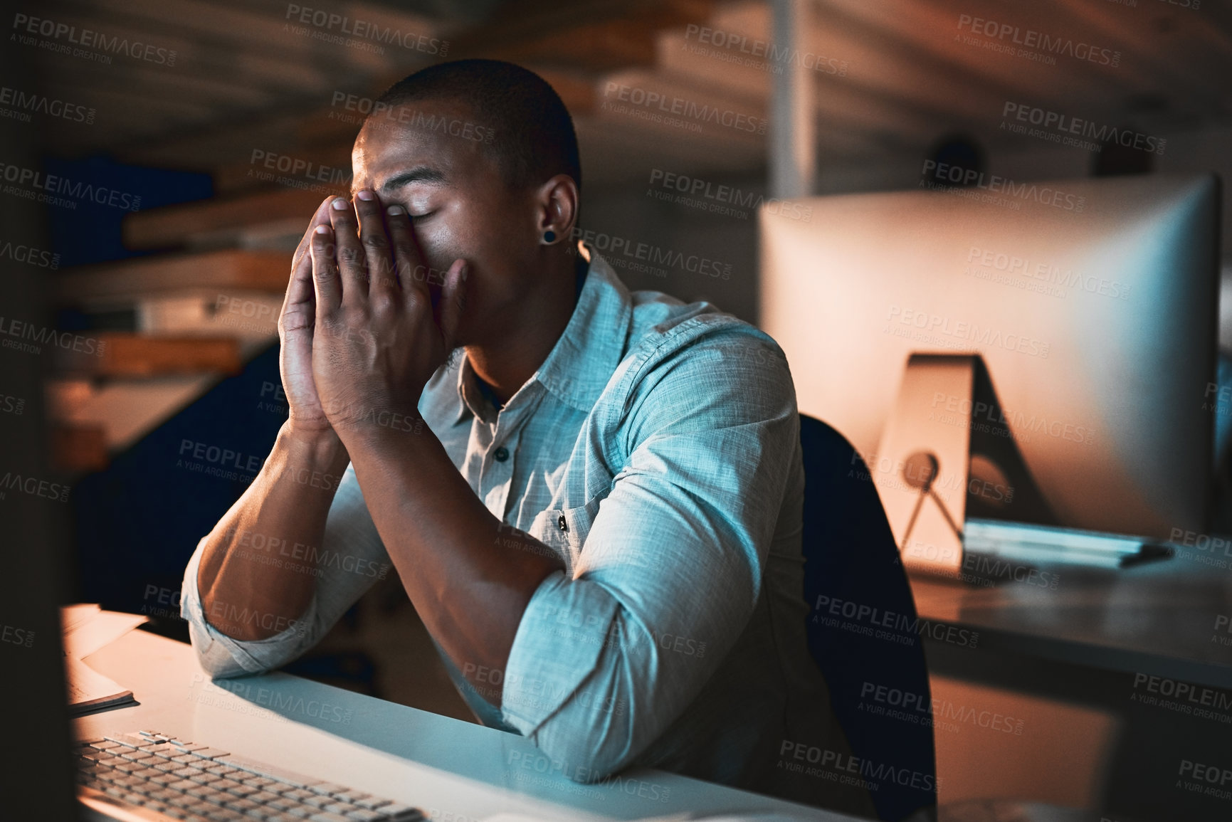 Buy stock photo Cropped shot of a young male designer looking stressed while working on his computer in the office