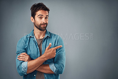 Buy stock photo Portrait, pointing and man with mockup, promotion and opportunity against a grey studio background. Face, male person and model with casual outfit, decision and choice with happiness and showing