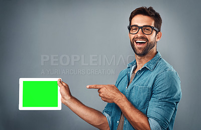 Buy stock photo Happy man, tablet and pointing on mockup green screen for advertising against a grey studio background. Portrait of male person with smile showing technology display, chromakey or copy space branding