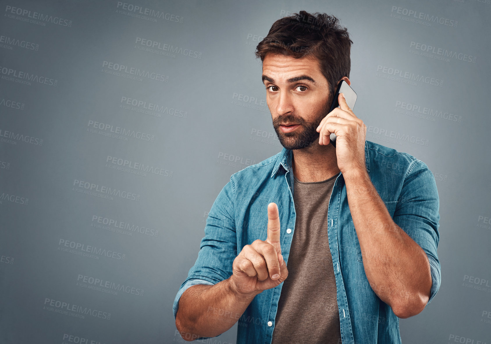 Buy stock photo Studio shot of a handsome young man using a mobile phone against a grey background