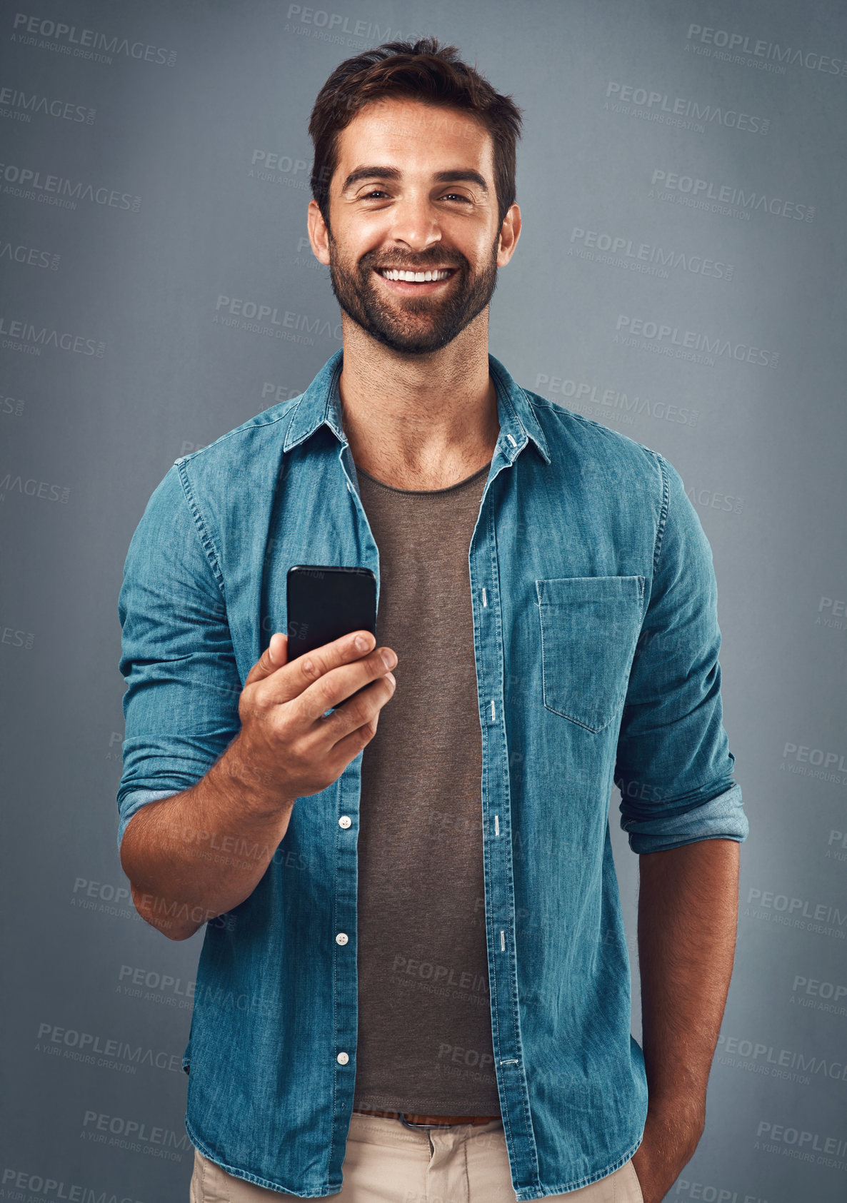 Buy stock photo Studio shot of a handsome young man using a mobile phone against a grey background