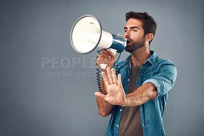 Buy stock photo Studio shot of a handsome young man using a megaphone against a grey background