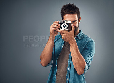 Buy stock photo Studio shot of a handsome young man using a camera against a grey background
