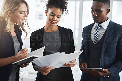 Buy stock photo Shot of a group of businesspeople going through paperwork together in an office