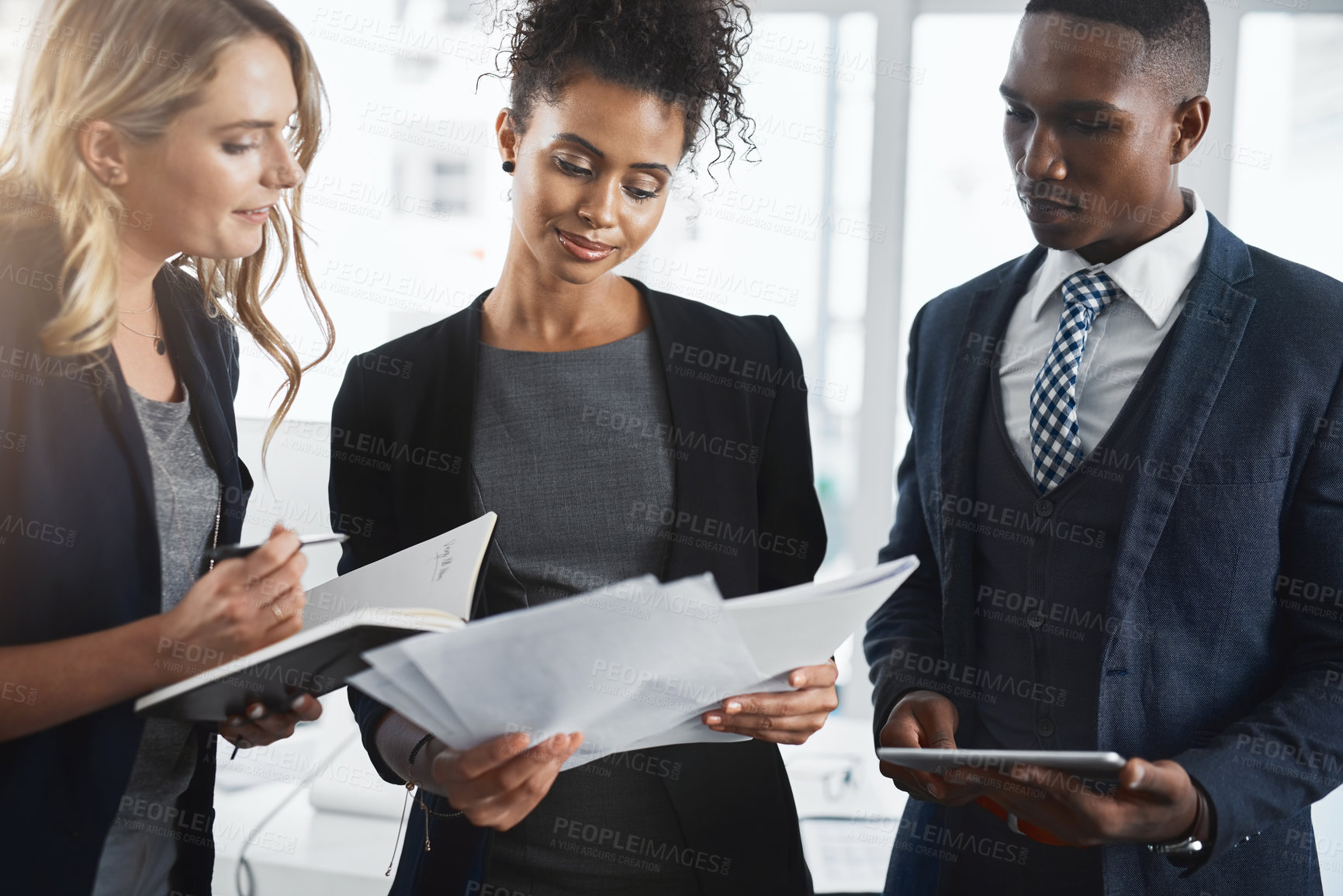 Buy stock photo Shot of a group of businesspeople going through paperwork together in an office