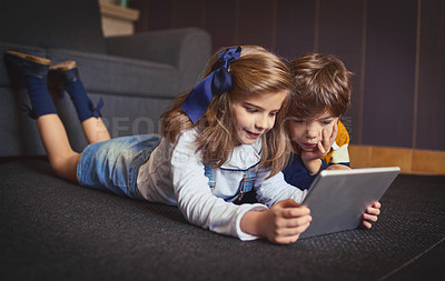 Buy stock photo Shot of a little boy and girl using a digital tablet at home
