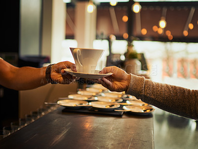 Buy stock photo Shot of an unrecognizable barman handing over a cup of coffee over the counter to a customer inside of a restaurant during the day
