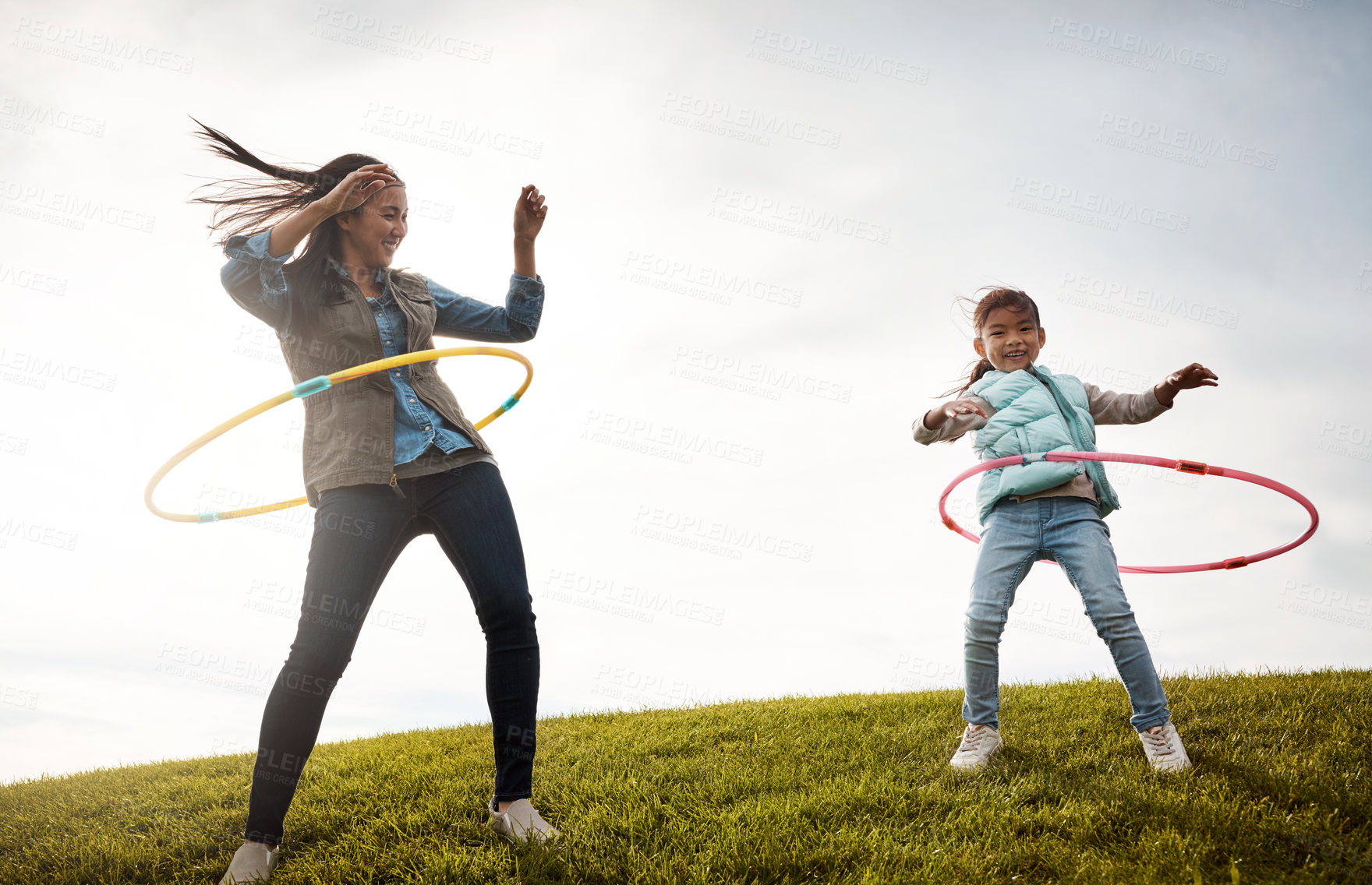 Buy stock photo Shot of a little girl and her mom having a hula hoop challenge