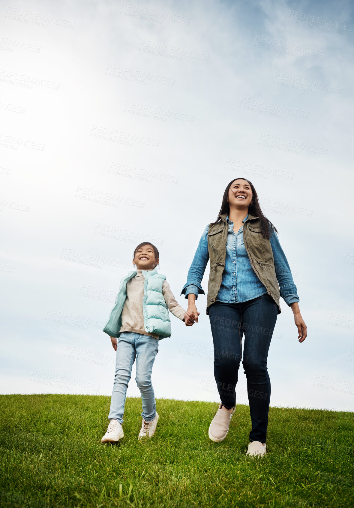 Buy stock photo Shot of a woman holding her little girl's hand as they walk outdoors