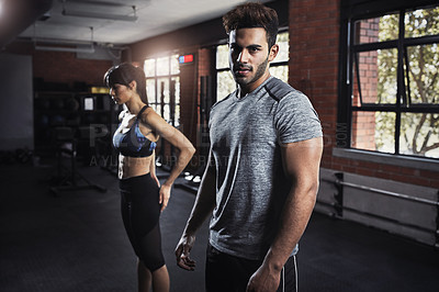 Buy stock photo Shot of two young people working out at the gym