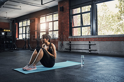 Buy stock photo Shot of an attractive young woman sitting on a exercise mat at the gym