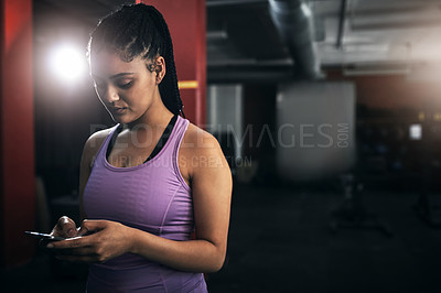 Buy stock photo Shot of a young woman using her cellphone at the gym