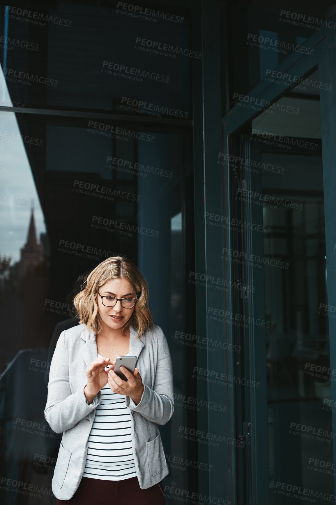 Buy stock photo Shot of a young businesswoman using her cellphone on the office balcony