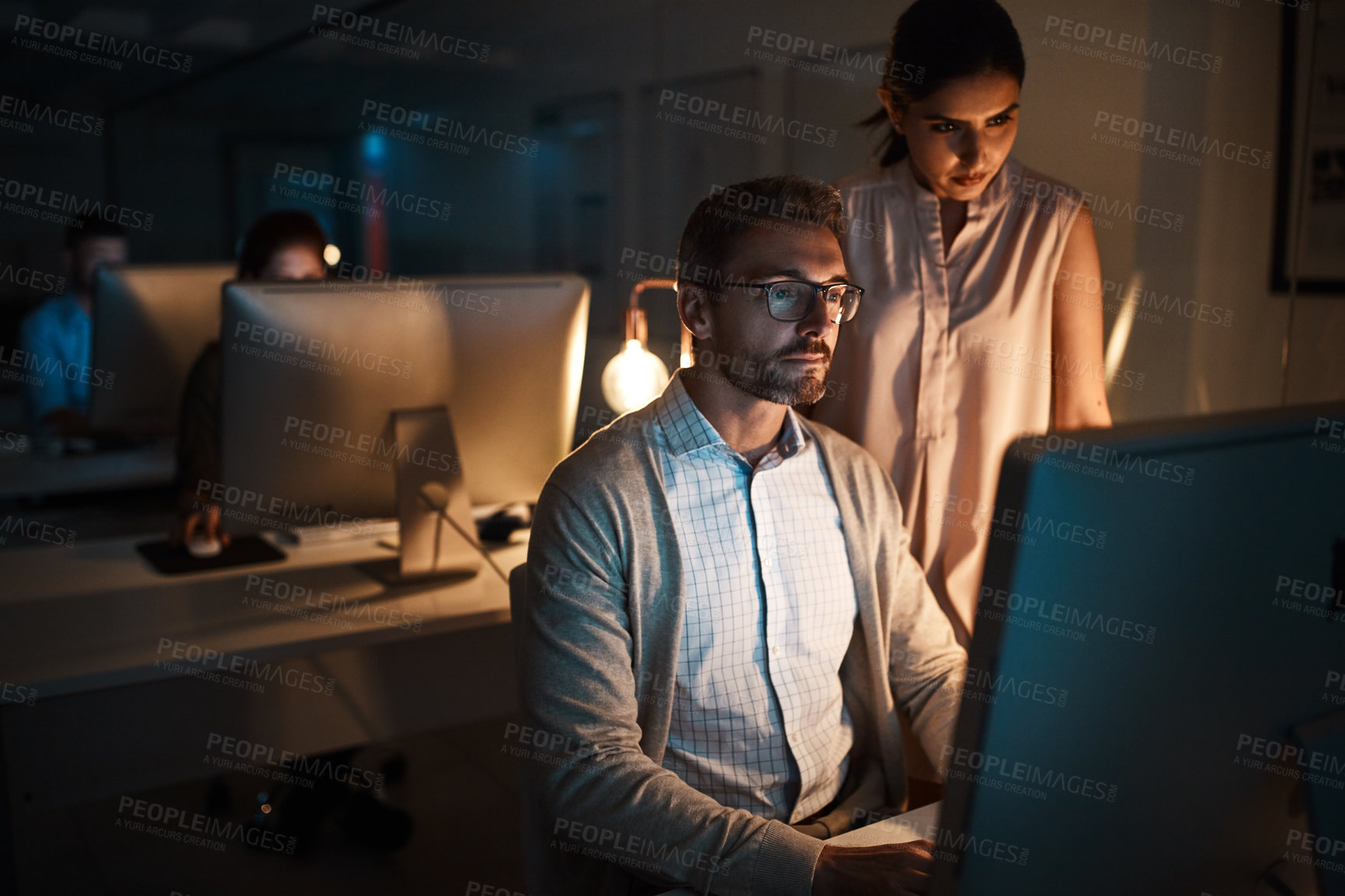 Buy stock photo Shot of two businesspeople working late on a computer in an office