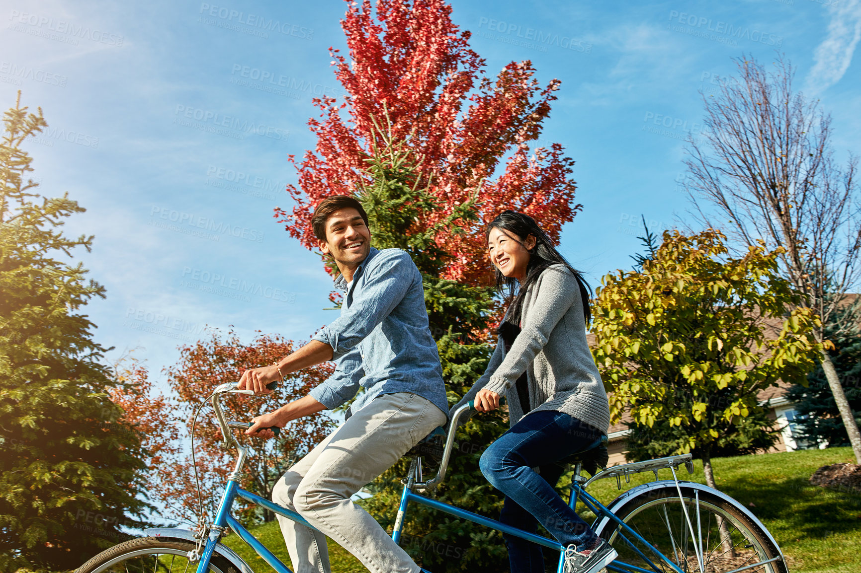 Buy stock photo Shot of a young couple out for a ride on a tandem bicycle
