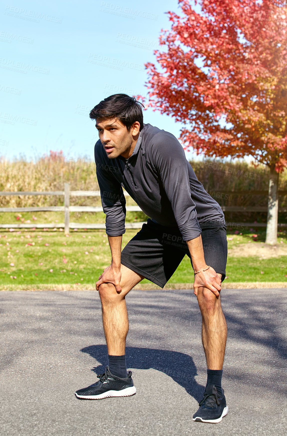 Buy stock photo Shot of a sporty young man taking a break while exercising outdoors