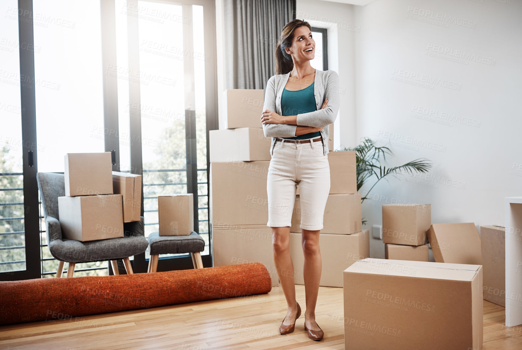 Buy stock photo Full length shot of an attractive young woman standing with her arms folded while moving into a new house