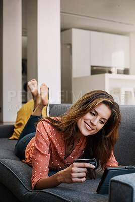 Buy stock photo Shot of an attractive young woman using a digital tablet and credit card on the sofa at home