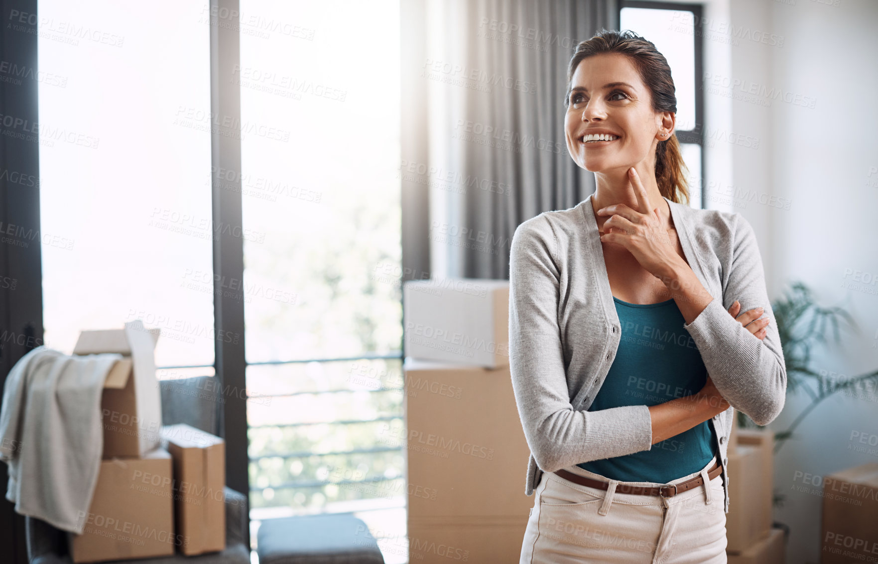 Buy stock photo Cropped shot of an attractive young woman looking thoughtful standing in her new home while moving in