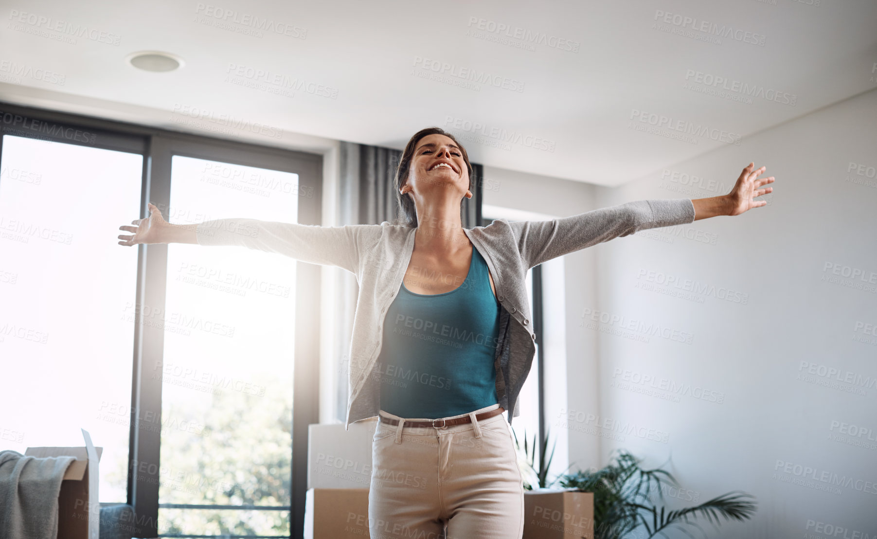 Buy stock photo Cropped shot of an attractive young woman standing with her arms outstretched while moving into a new house