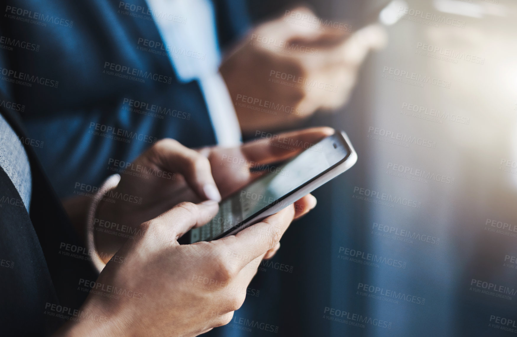 Buy stock photo Closeup shot of two unrecognizable businesspeople using their cellphones in an office