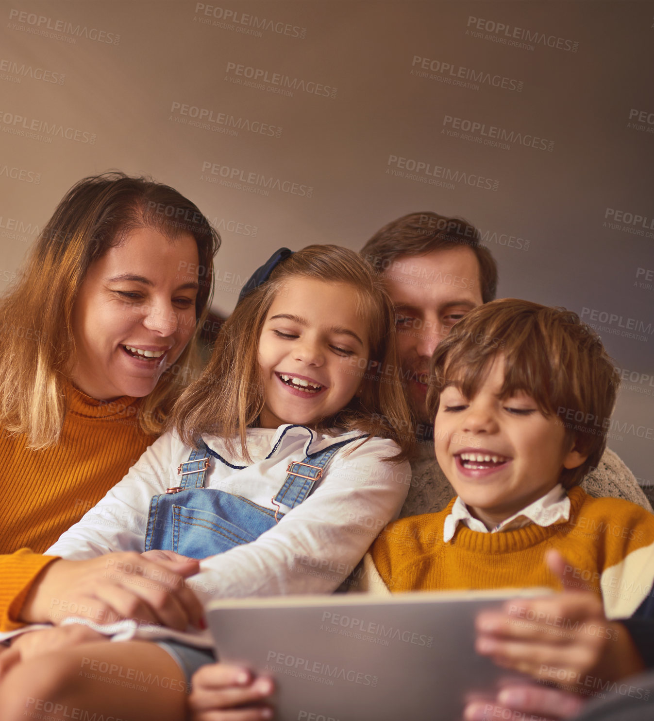Buy stock photo Cropped shot of an affectionate young family of four using a digital tablet while sitting on the sofa at home